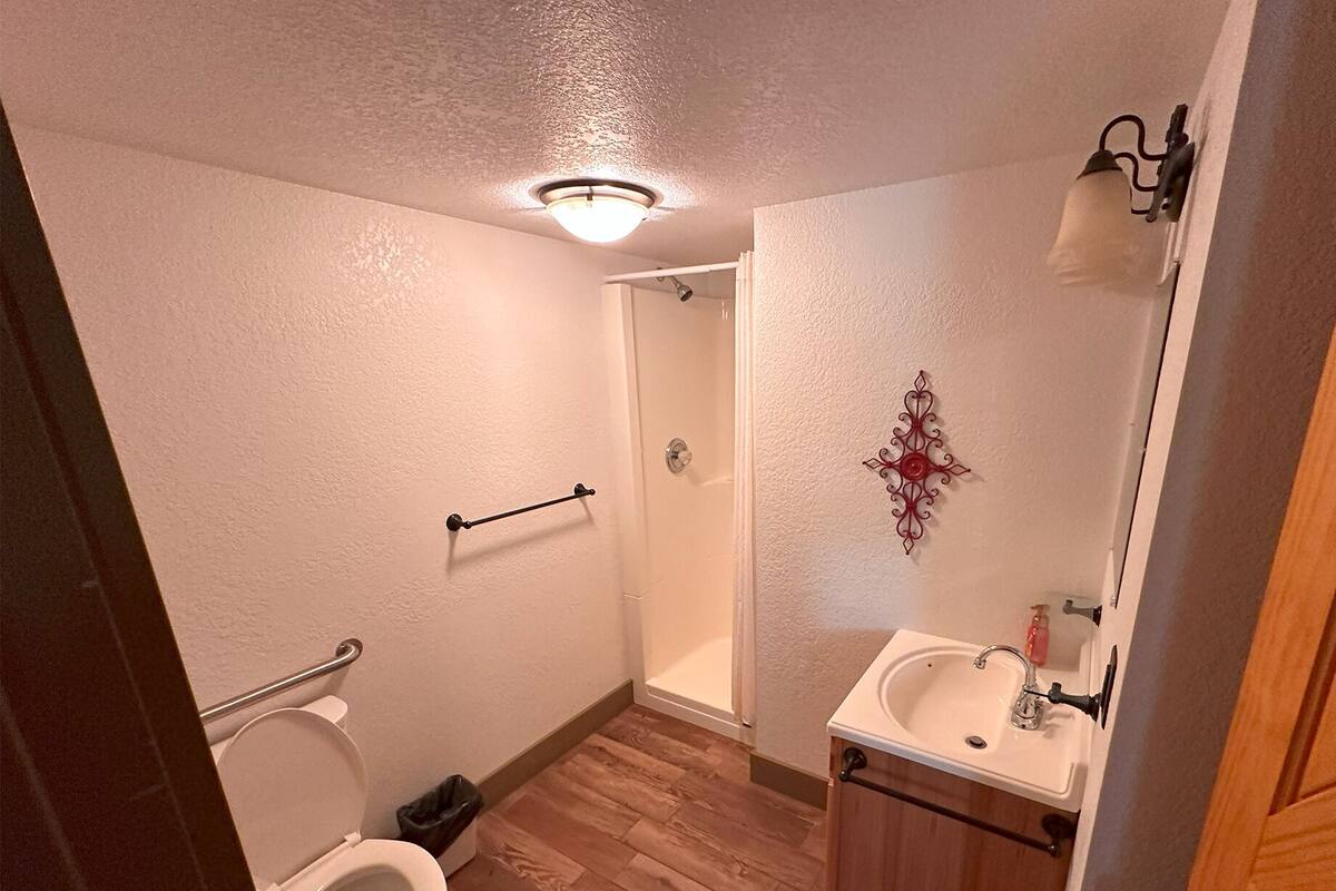 A bathroom with a toilet, a shower, and a sink.