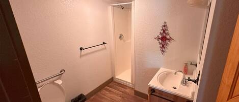 A bathroom with a toilet, a shower, and a sink.