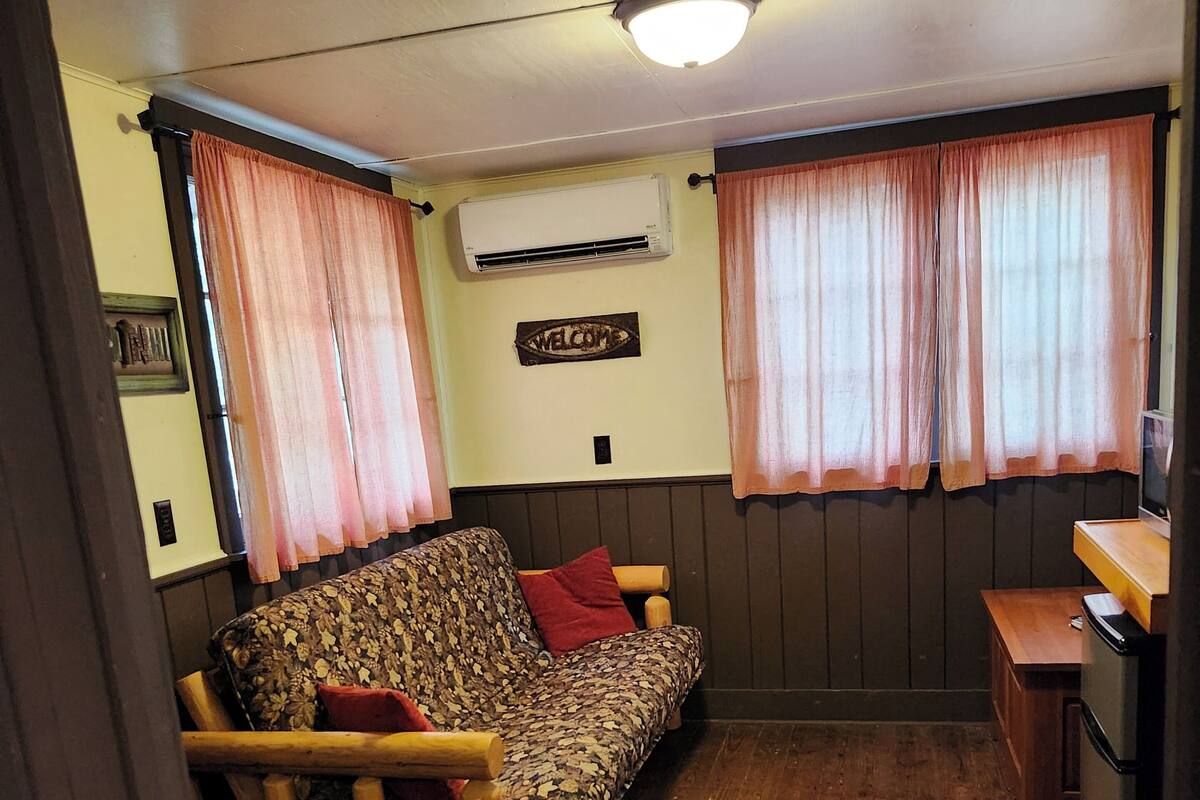 A cozy room with a patterned sofa, wooden chair, and a small wooden table.
