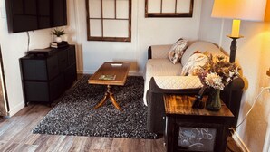 A living room with a sofa, a coffee table, a TV, and a lamp. - NEWLY UPDATED Quiet Cottage Near Turkey Point and Port Dover (Simcoe)