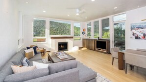 A spacious living room with a fireplace, large windows, and a modern kitchen area. - Telluride Sunset Ridge Home Spacious and Quiet! View of the Valley Floor and Wildlife (Telluride)