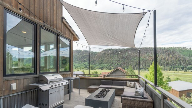 A covered outdoor patio with a grill, seating, and a view of a forested area. - Telluride Sunset Ridge Home Spacious and Quiet! View of the Valley Floor and Wildlife (Telluride)