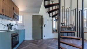 A modern kitchen with wooden cabinets, a built-in oven, and a herringbone-patterned floor. - Duplex Bénézet - Welkeys (Avignon)