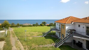 A coastal property with a sea view, a grassy yard, and a building with a tiled roof.