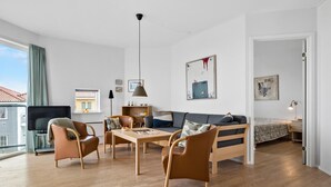 A modern living room with a sofa, two chairs, a coffee table, and a TV.
