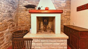 A stone fireplace with a white mantel, a wooden bench, and a wooden cabinet to the right.