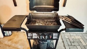 Kannettava grilli, jossa on ohjauspaneeli ja sivupöytä, ja taustalla näkyy puinen seinä.
