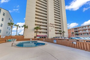 A hotel with a swimming pool, palm trees, and a parking lot. - Atalaya Towers 1106 - Oceanfront in Garden City Beach (Garden City Beach)