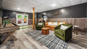 Un rincón acogedor con mesa de billar, sillones verdes, una mesa de centro de madera y dardos.