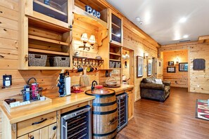 Un intérieur en bois comprenant un espace cuisine, avec un évier, une enseigne de bar et un réfrigérateur à vin.