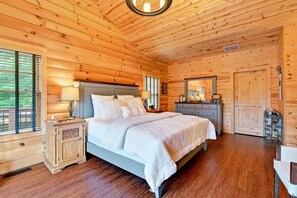 A wooden-paneled bedroom with a bed, bedside tables, and a dresser.