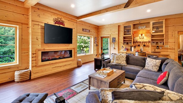 Ein gemütliches Blockhaus-Interieur mit Kamin, einer Sitzecke, einem Fernseher und einer Bar.