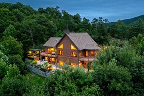 Eine zweistöckige Holzhütte mit mehreren Balkonen und einer Terrasse, umgeben von dichtem Wald.