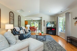 A living room with a black leather sofa, a patterned armchair, a coffee table, and a fireplace.