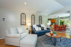 A living room with a sofa, a coffee table, and a dining area with chairs and a table.