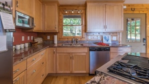 A kitchen with wooden cabinets, a stainless steel sink, a microwave, and a dishwasher.