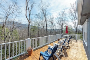 A wooden deck with white railings, outdoor furniture, and a view of trees and hills. - Stone Circle Cottage | Dog-Friendly + 5 Min. to Black Mountain! (Black Mountain)