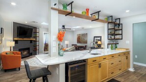 Een moderne keuken met een centraal eiland, houten kastjes en ingebouwde planken.