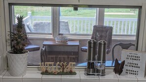 A kitchen with a window view of outdoor seating, a welcome sign, and kitchen essentials like a coffee maker and dish soap. - Comfy Country home. Pet friendly, 5 bedrooms, AC, WIFI, just outside Farmington  (Farmington)