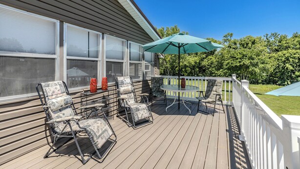 A covered deck with outdoor furniture, a table, and a large umbrella. - Comfy Country home. Pet friendly, 5 bedrooms, AC, WIFI, just outside Farmington  (Farmington)