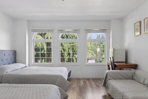 A bedroom with three beds, large windows, a desk, and a chair. - Master Bedroom 208 Located in Burnaby (Metrotown Area) (Burnaby)