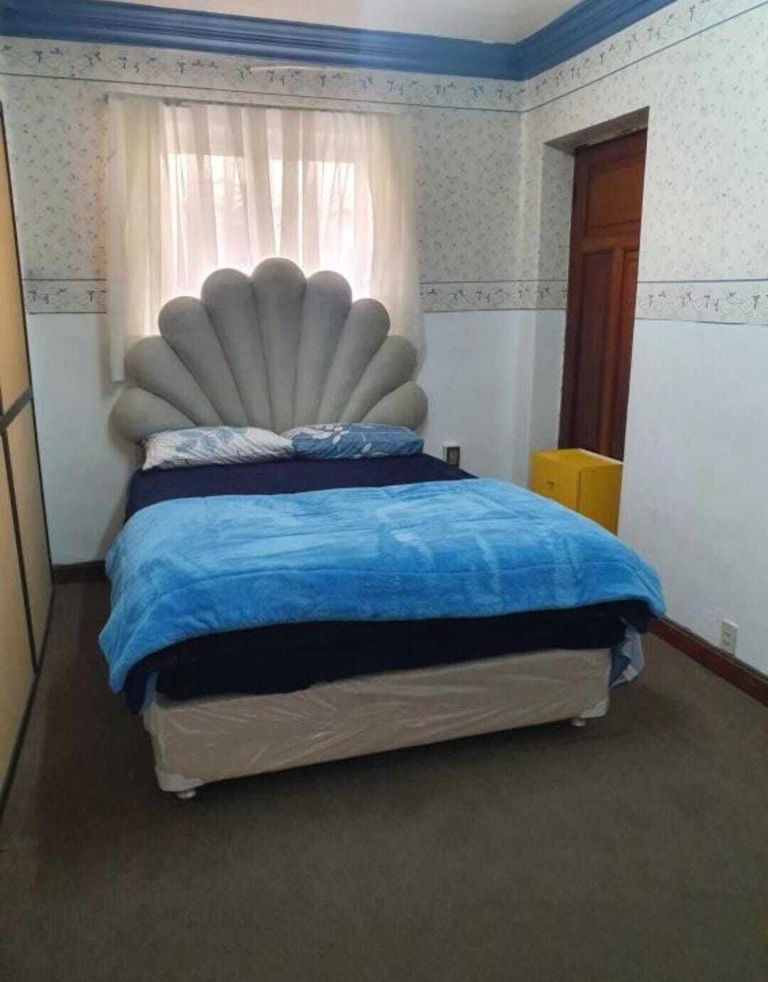 Een slaapkamer met een bed, een raam met gordijnen, een deur en een behang met patroon.