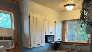 Una cocina con armarios blancos, encimera de granito, microondas y cafetera.