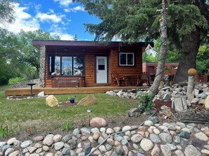 Una cabaña de troncos con terraza, mobiliario exterior y un sendero de piedra.