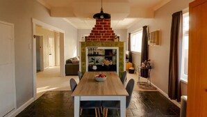 Een eetgedeelte met een open haard van baksteen, een houten tafel en stoelen.