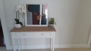 Een wit bureau met een houten blad, twee lades en een abstract schilderij in een lijst.