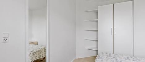 Een slaapkamer met een bed, een kledingkast en een spiegel.