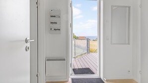 A room with a door leading to a balcony with a view of the sea. - Gudhjem Søpark Lejl. 16 (Gudhjem)