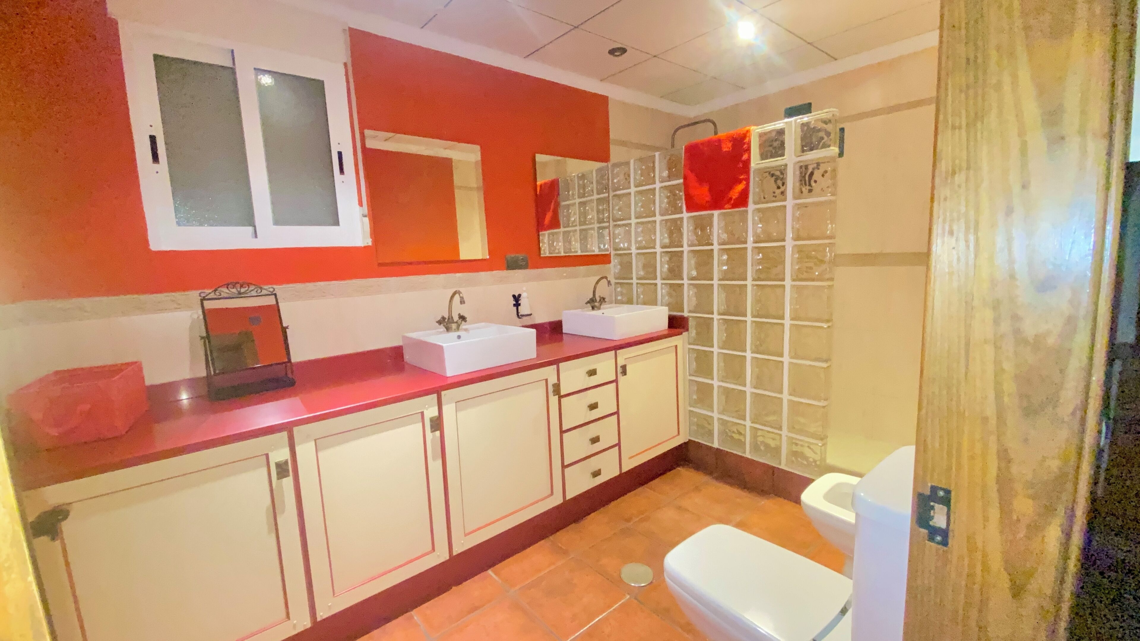 A bathroom with two sinks, a toilet, and a shower area.