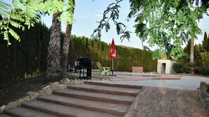 Una escalera de piedra que conduce a un patio con mobiliario exterior y un paraguas rojo.