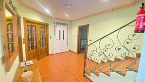 Un pasillo con suelo de baldosas, puertas de madera y una escalera de metal con barandillas decorativas.