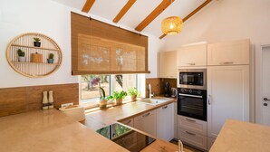 Eine moderne Küche mit Holzbalken, einem Einbauofen und einem Fenster mit einer Bambusjalousie.