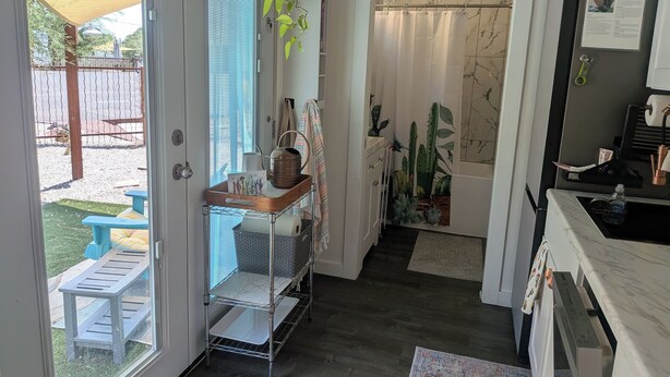 A kitchen with a marble countertop, a hanging plant, and a shower with a curtain.