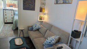 A living room with a sofa, a coffee table, a bookshelf, and a painting on the wall.