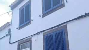 Een wit gebouw met blauwe luiken en een witte deur met decoratief detail.