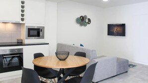 Een moderne keuken met een magnetron, oven en een eetgedeelte met een ronde tafel en stoelen.