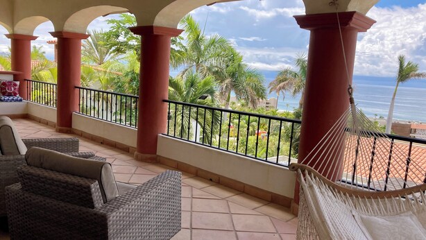 A balcony with wicker furniture, a hammock, and a view of the ocean. - Charming 5-bed house with sweeping ocean views in delightful San Jose Del Cabo. (San Jose Del Cabo)
