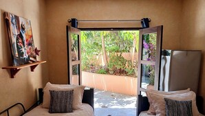 A bedroom with two beds, a painting on the wall, and a view of a garden through an open door. - Charming 5-bed house with sweeping ocean views in delightful San Jose Del Cabo. (San Jose Del Cabo)