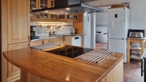 A modern kitchen with wooden cabinets, a built-in stove, and a white refrigerator. - Cozy home in Tjörn with sauna (Tjörn)