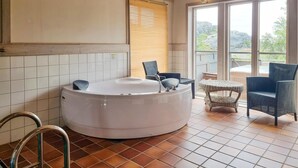 A spa area with a hot tub, wicker chairs, and a view of the outdoors. - Cozy home in Tjörn with sauna (Tjörn)