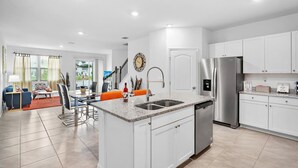 Una cocina moderna con armarios blancos, un refrigerador de acero inoxidable y un lavavajillas empotrado.