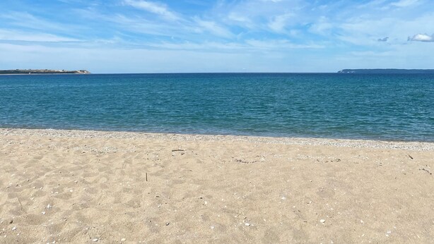 A beach with clear skies and calm water. - Sleeping Bear Beauty! Fully Remodeled Beachfront Condo with summer availability  (Glen Arbor)