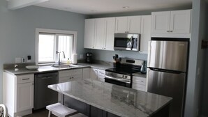 A modern kitchen with white cabinets, stainless steel appliances, and a marble countertop. - Sleeping Bear Beauty! Fully Remodeled Beachfront Condo with summer availability  (Glen Arbor)