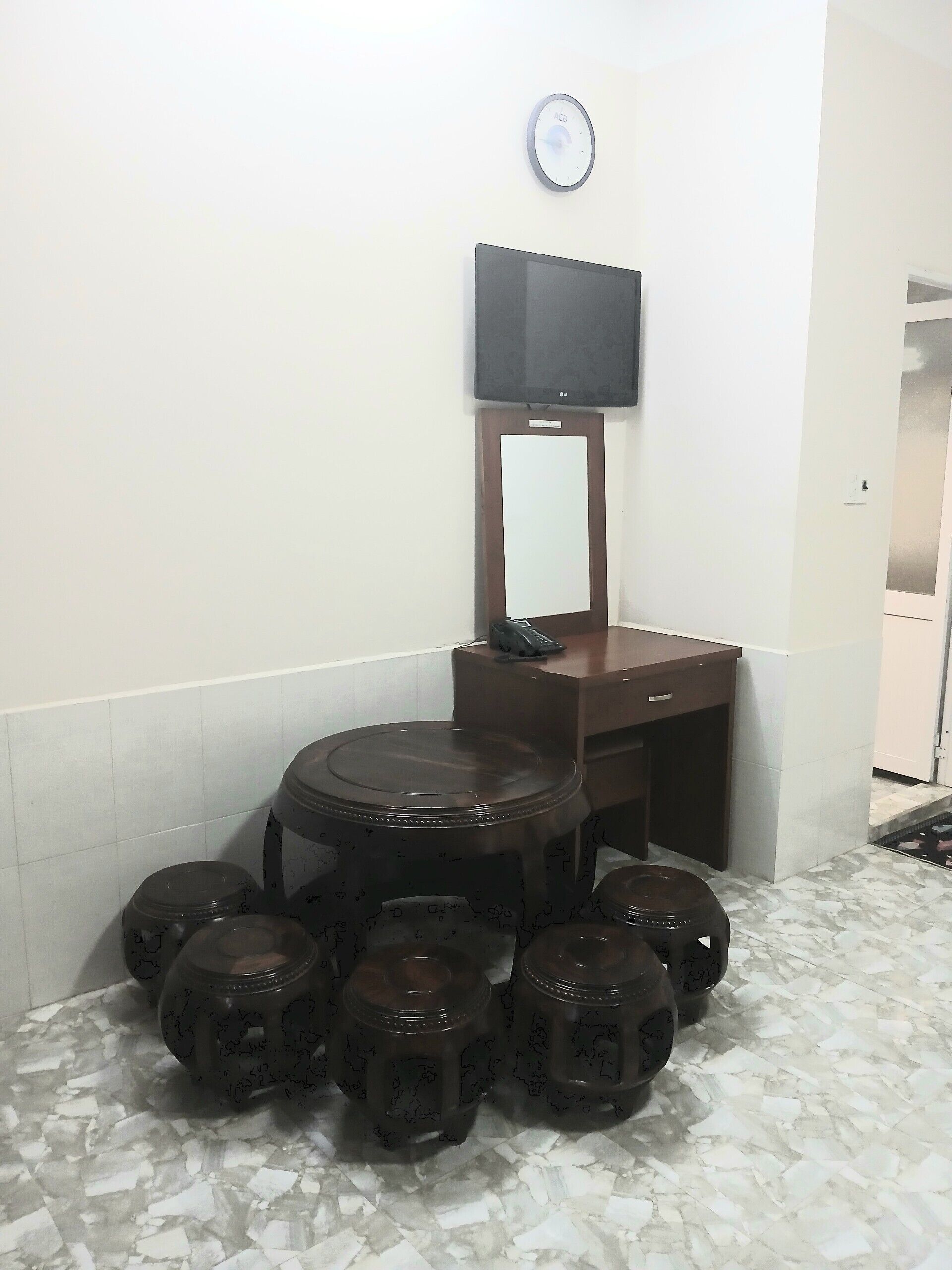 A bathroom with a toilet, a sink, a mirror, and a television mounted on the wall.