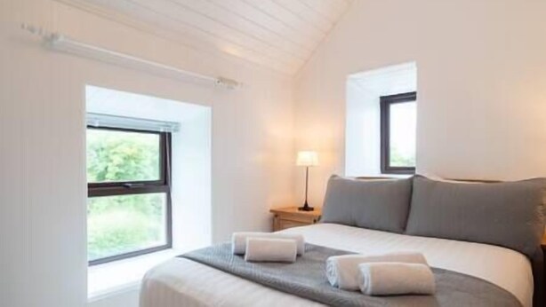 A bedroom with a bed, two windows, a nightstand, and a lamp. - Countryside Retreat Dingle (Municipal District of Castleisland-Corca Dhuibhne)