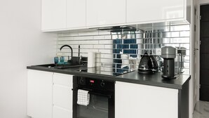 A modern kitchen with white cabinetry, a black countertop, and a stainless steel backsplash. - Plac Politechniki Cosy Studio (Warszawa)